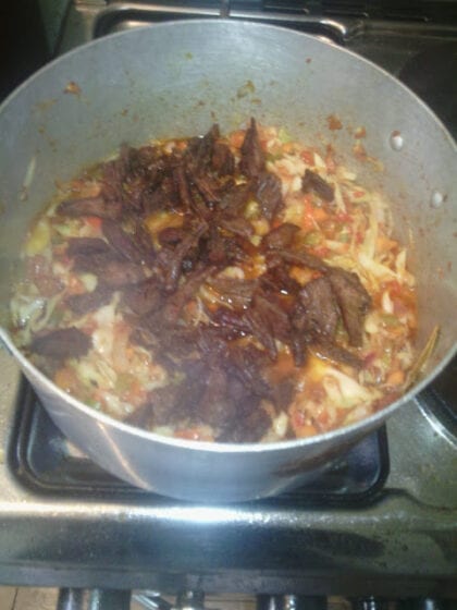 adding fried meats to pot of sauce