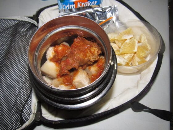 Nigerian school lunchbox meal of boiled yam with stew and a side of oranges