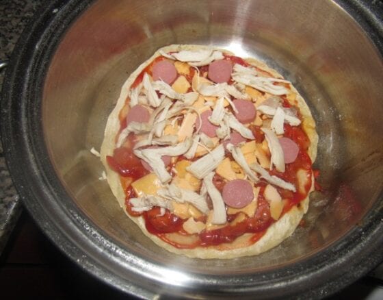 Pizza toppings on the cooking pot pizza sitting on a burner