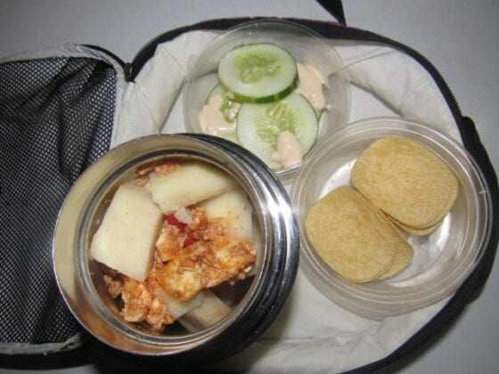 Nigerian school lunchbox meal of boiled yam with egg sauce and springle snack