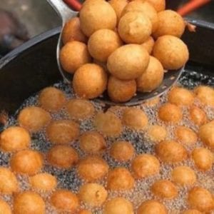Nigerian puff being fried in a large pot 