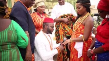 Showing a traditional nigerian wedding with the groom kneeling before his bride for exchange of rings